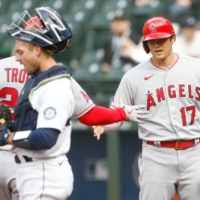 Angels designated hitter Shohei Ohtani (right) celebrates with teammate Mike Trout after scoring on Trout's home run against the Mariners on Saturday in Seattle. | USA TODAY / VIA REUTERS