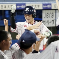 Naomichi Nishiura is greeted by his Swallows teammates in the dugout after hitting a solo home run against the Giants on Tuesday at Jingu Stadium. | KYODO