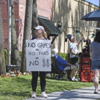 A fan holds a protest sign outside a building hosting negotiations between MLB officials and the player's union in Jupiter, Florida, on Feb. 28. | 　米大リーグの労使交渉が行われている施設前で、抗議のボードを手にするファン＝２月２８日、フロリダ州ジュピター（共同）