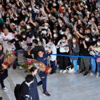 Hundreds of fans crowd together and cheer as members of the Japanese national baseball team arrive at Narita Airport in China Prefecture on Thursday. | AFP-JIJI